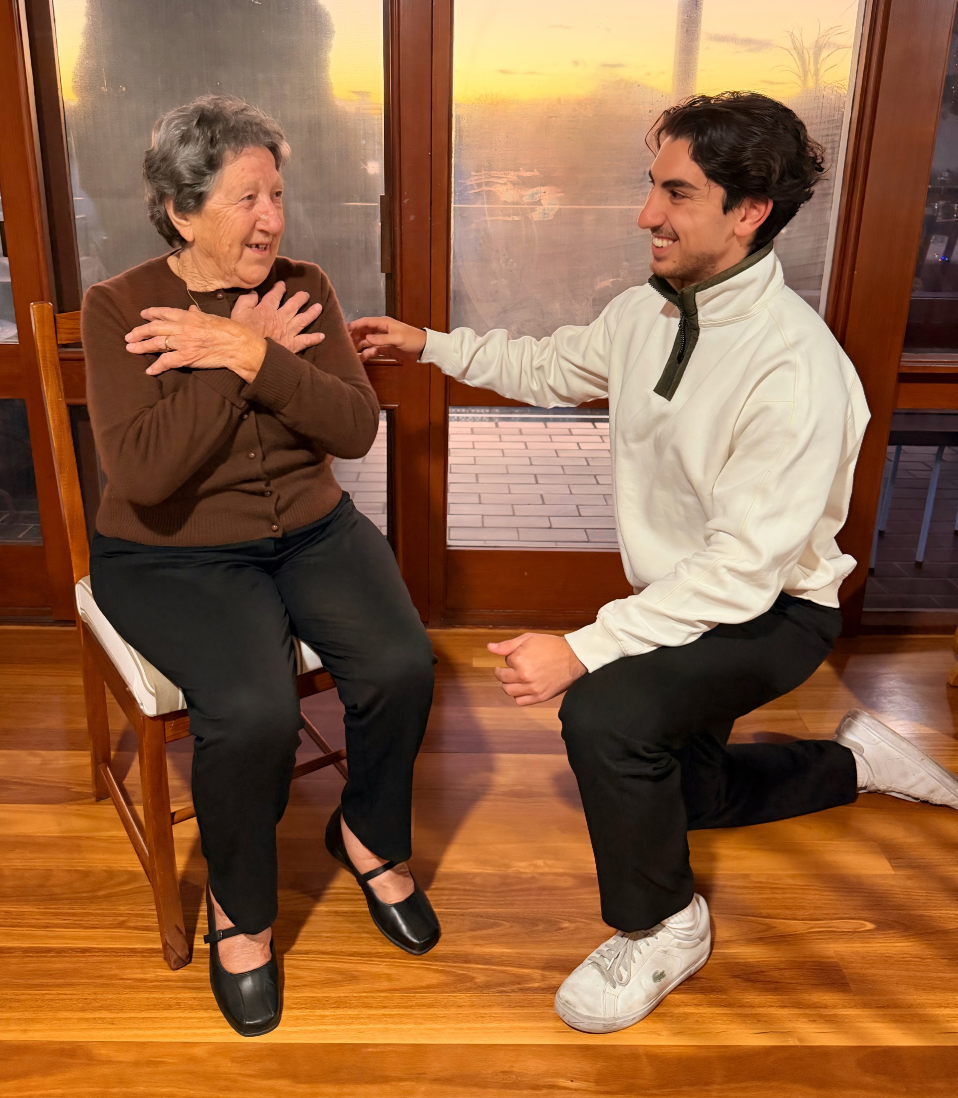 Adrian Alifano, exercise physiologist, kneeling beside an older client in her home.